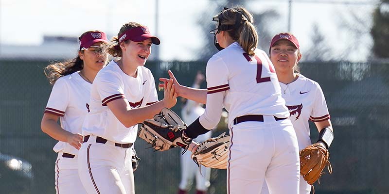 Kenna Davis, second from left, celebrates with several other Willamette infielders.