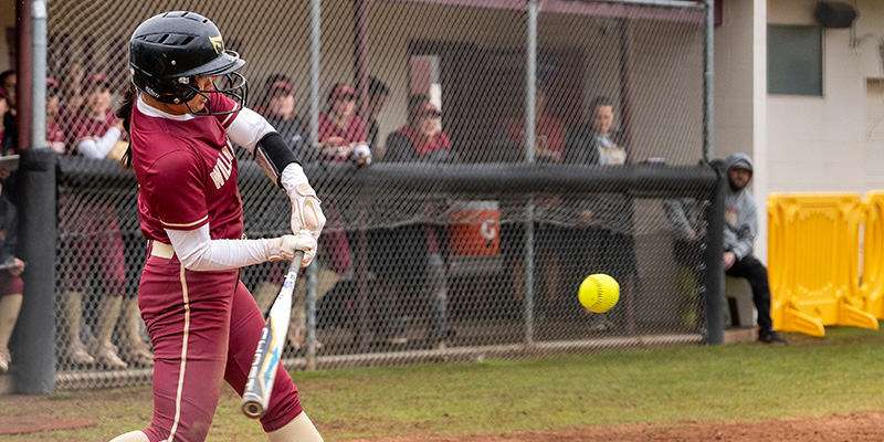 Closeup of Mia Lund starting to swing as the ball approaches home plate.