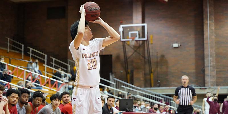 Ryder Hsiung of Willamette is about to release a three-point shot near the sideline.