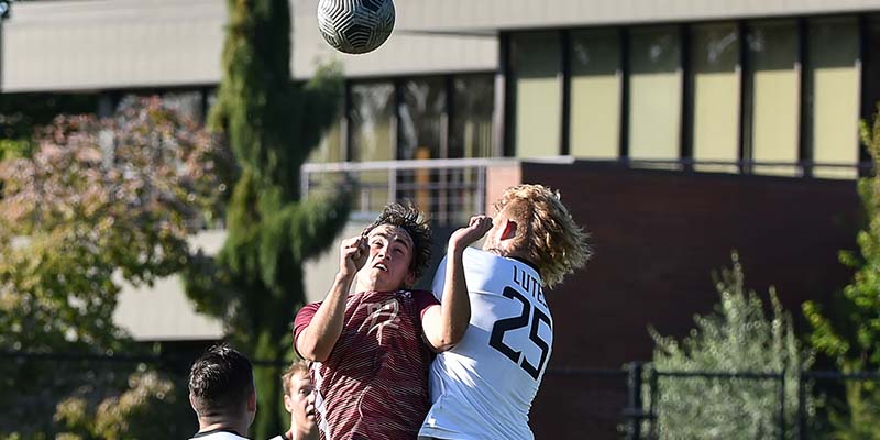 Jett Starr goes up for a header while battling a Pacific Lutheran defender.